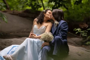 Bride and groom share a tender kiss on a rock in Central Park during their New York City elopement