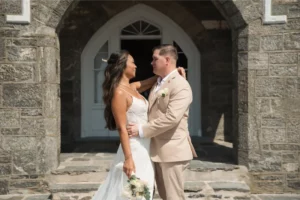 Bride and groom embrace outside a historic stone building during their New York City elopement.