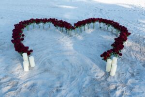 Miami Beach proposal setup with heart shape made of red roses and candles arranged on the sand