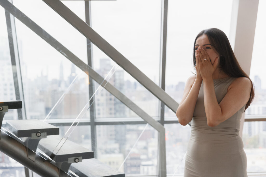 Woman reacting emotionally during a surprise proposal in NYC with skyline views